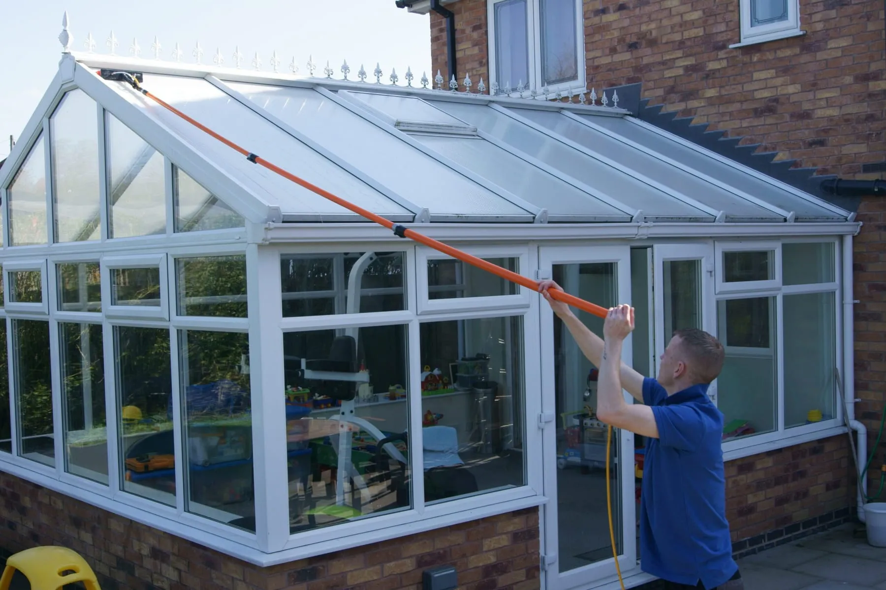 An operative cleaning a conservatory roof from the ground with an extending pole