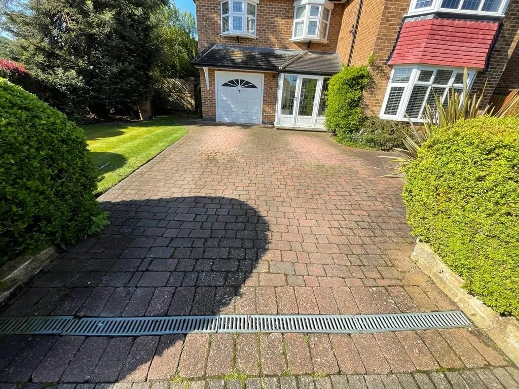 A block-paved driveway before cleaning, dark and weathered