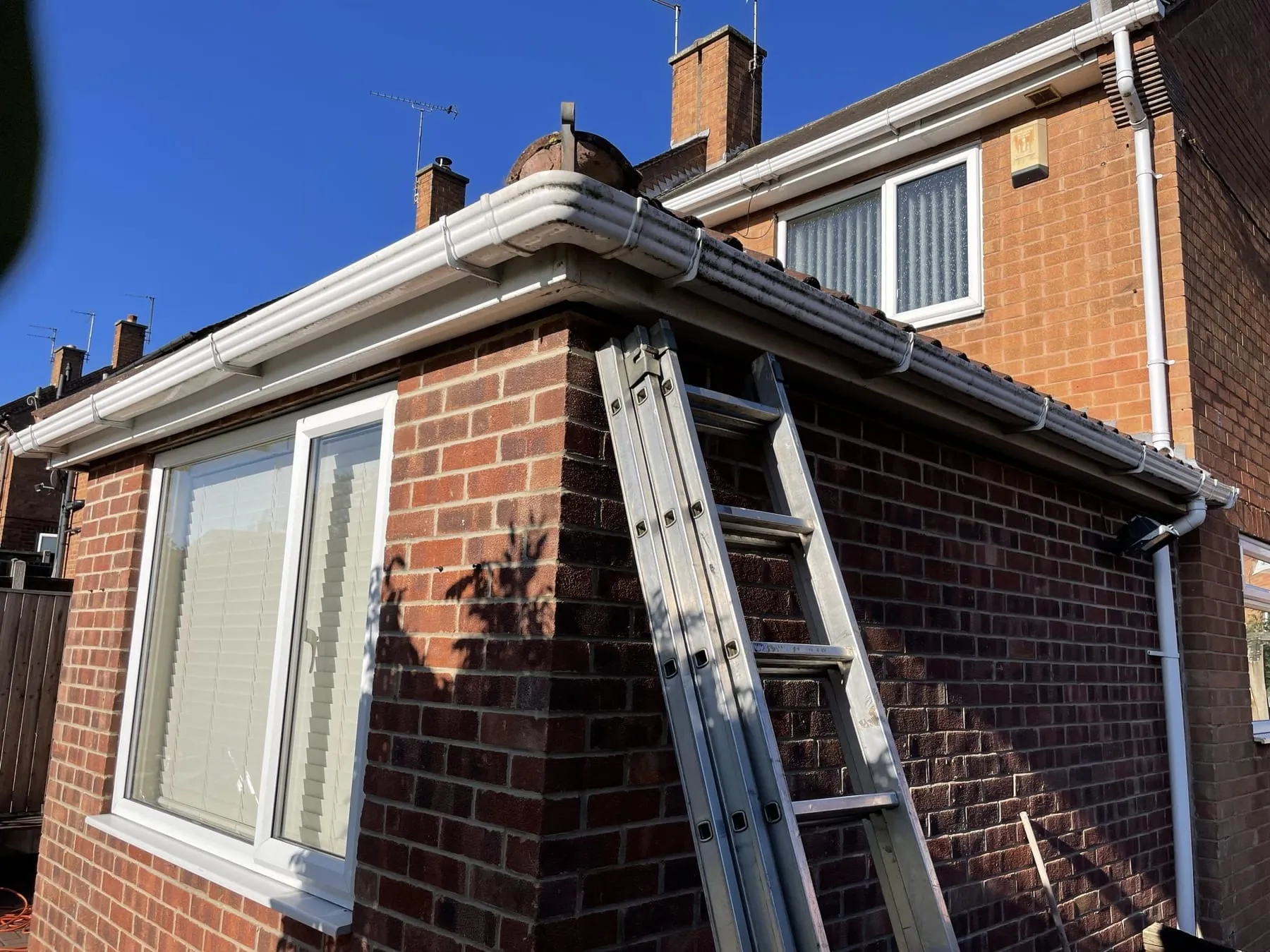 Gutter being cleared from ground level with a vacuum pole