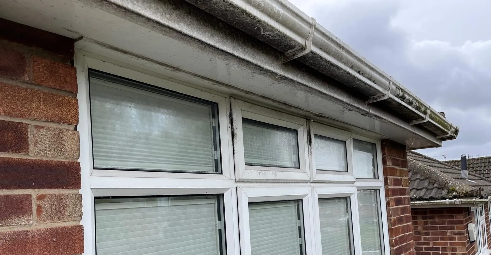 A bungalow soffit and gutter streaked with dirt before cleaning