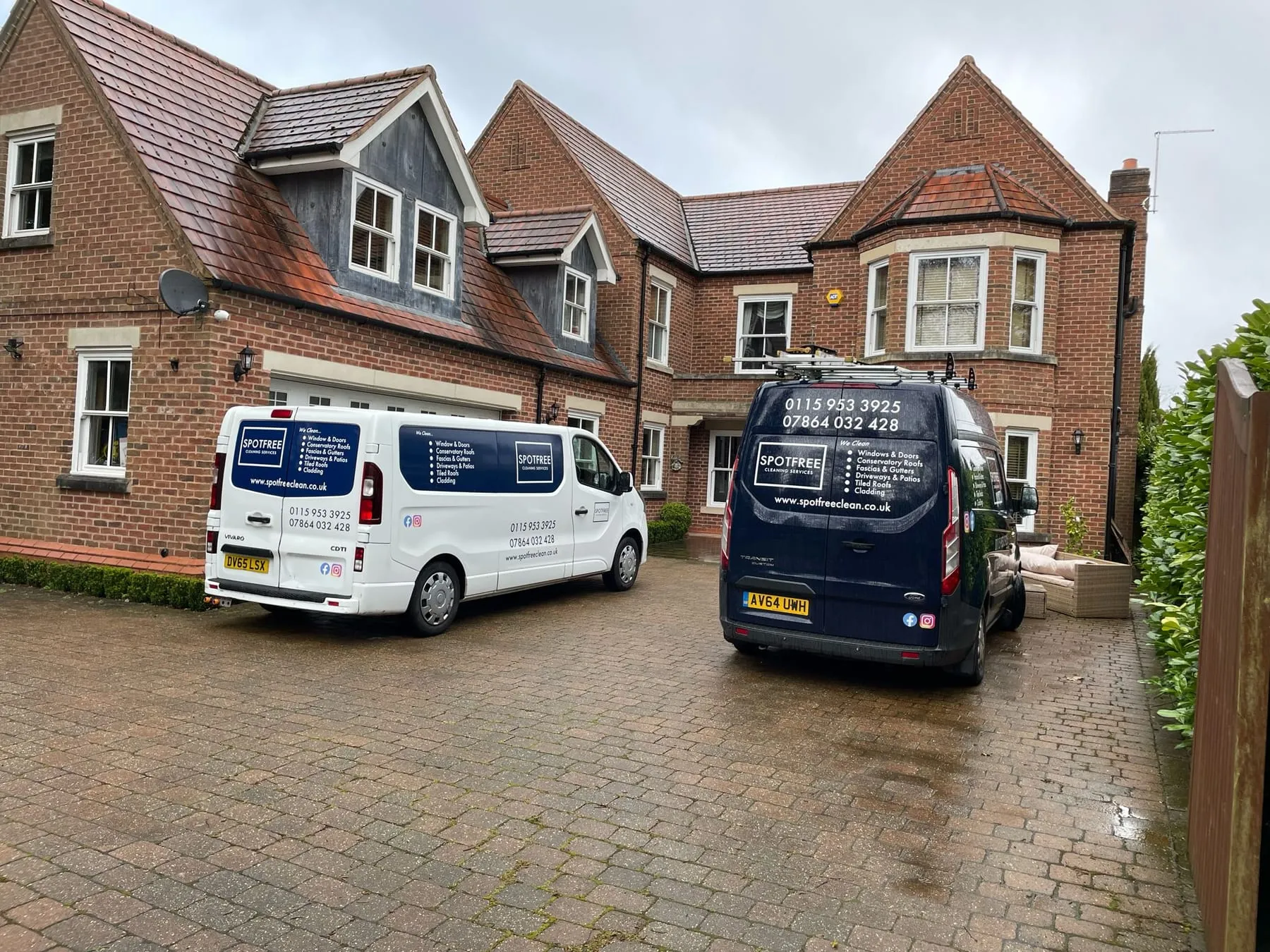 Two SPOTFREE vans parked on the block-paved drive of a large detached house